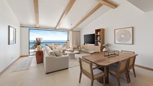 Un amplio salón con balcón, una mesa de comedor y un televisor.