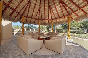 A covered outdoor seating area with stone flooring and a thatched roof. - Ocean View 3 BR Penthouse with Private Jacuzzi at Puerta del Sol, Cabo San Lucas (Cabo San Lucas)