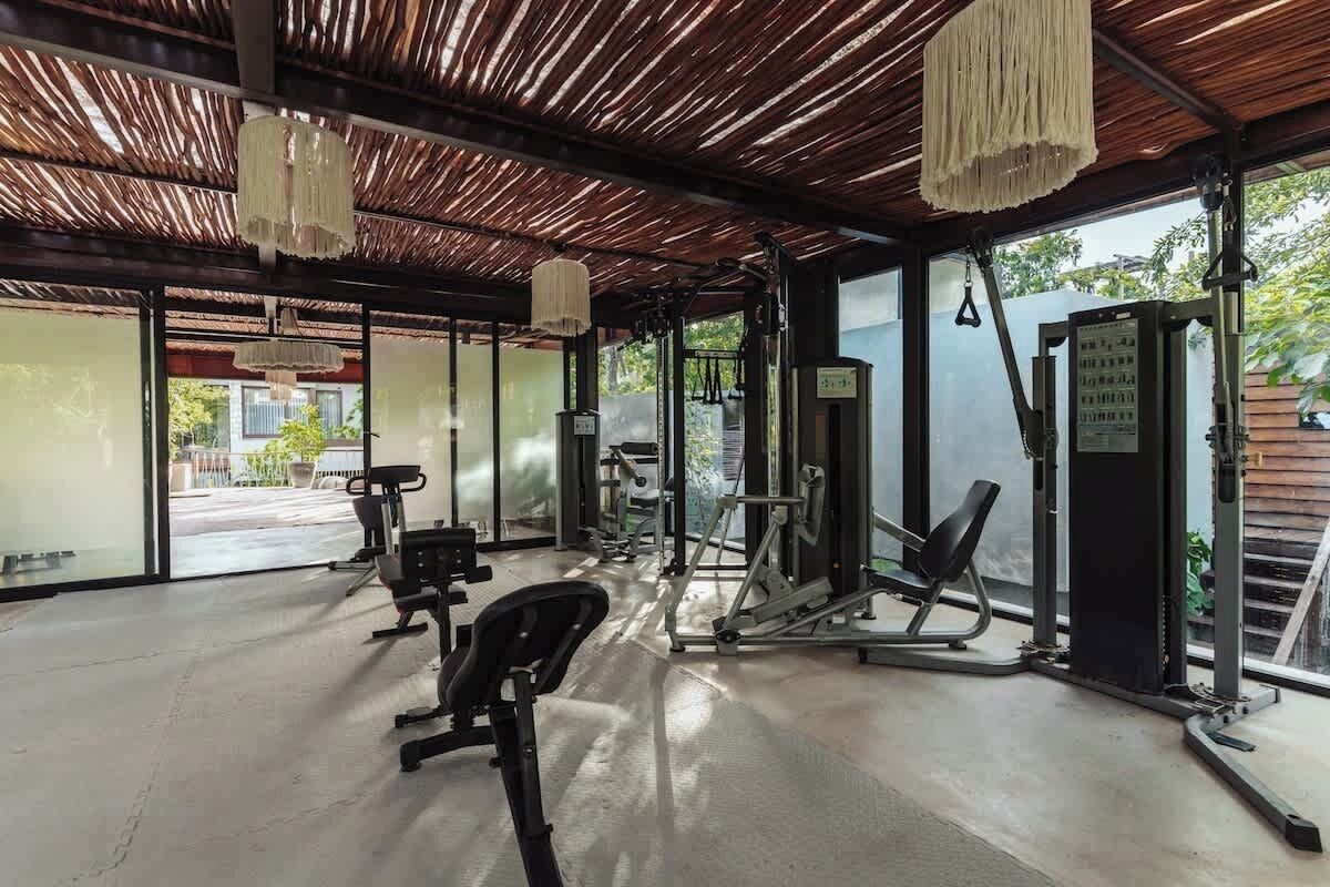 Une salle de sport équipée de matériel d’exercice, dotée de grandes fenêtres et d’un plafond en bois.