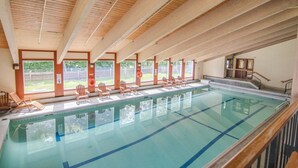 An indoor swimming pool with wooden beams, clear water, and sunlit windows. - Home at Waterville Estates- tons of amenities! (Campton)