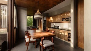 A modern kitchen with wooden cabinets, a dining table with chairs, and a hanging light fixture.