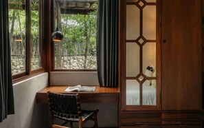 A room with a wooden desk, a chair, a window with curtains, and a traditional wooden cabinet. - Siwa Jungle Rain A2-004 Beach Club Access (Tulum)