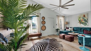Ein Wohnzimmer mit Deckenventilator, einer Couch, einem Couchtisch und einem Zebra-Teppich.