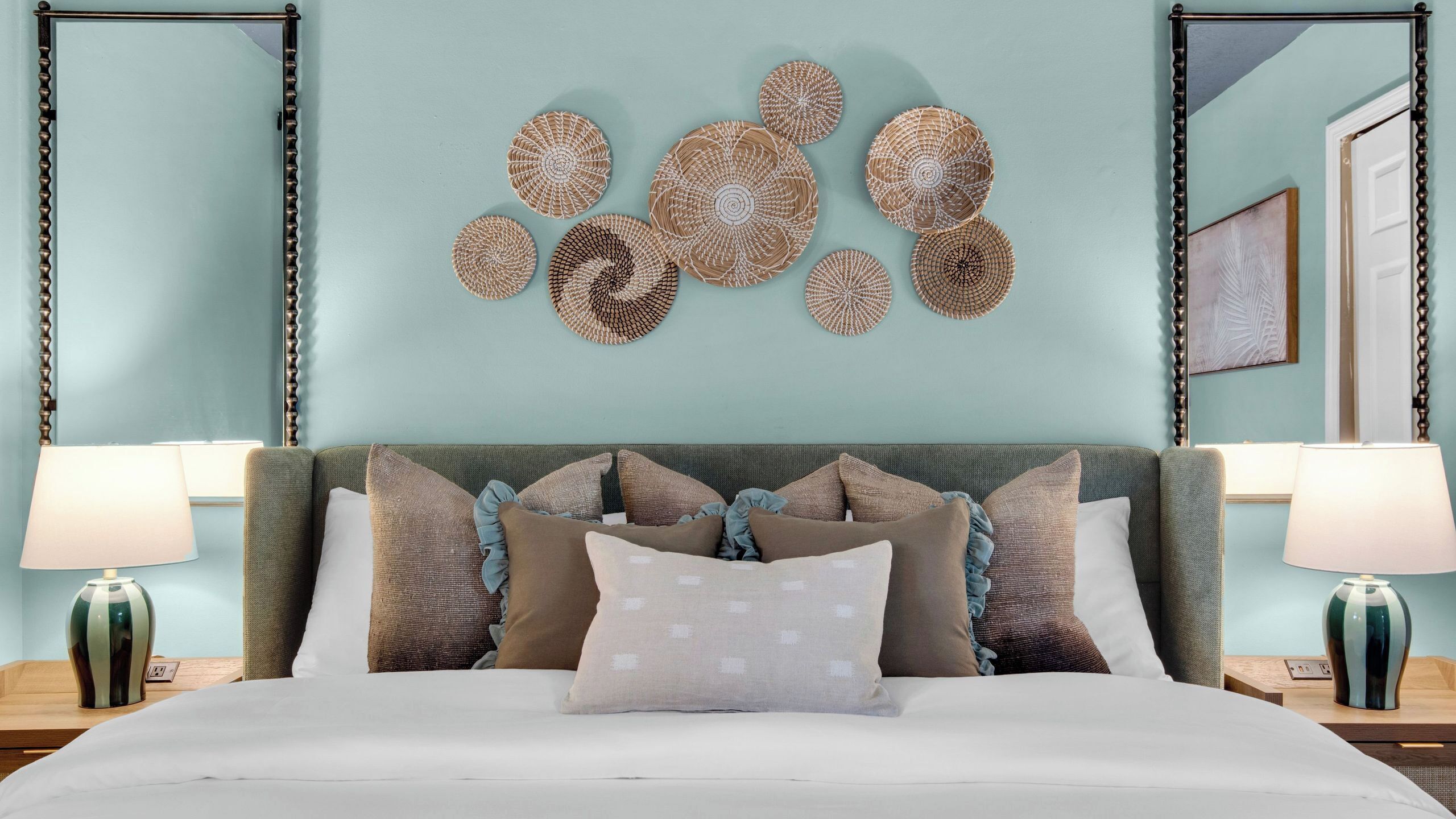 Un lit avec une tête de lit, deux tables de chevet et un mur orné d’œuvres d’art décoratives.
