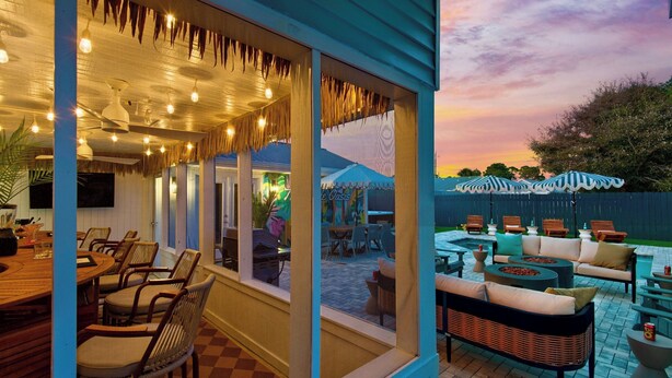 Ein Restaurant mit Terrassenbereich, Außenplätzen und Blick auf den Sonnenuntergang.