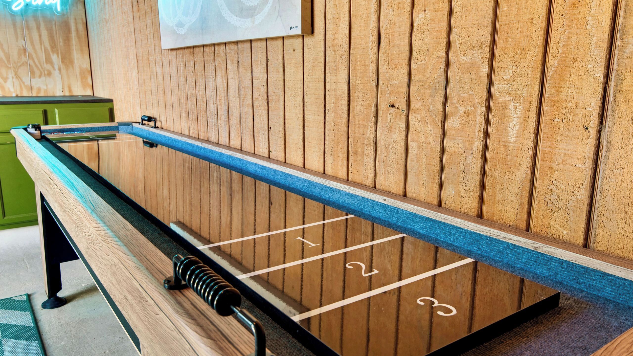 Une table de billard avec un fond en bois et un meuble vert sur le côté gauche.