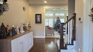 Een ruime woonkamer met een houten trap, een kerstboom en een kerststal.