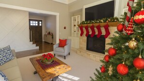 Een woonkamer met een open haard, kerstboom en een bank.
