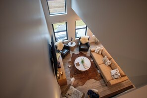Una sala de estar moderna con un sofá de cuero marrón, una mesa de centro redonda y un sillón de cuero.
