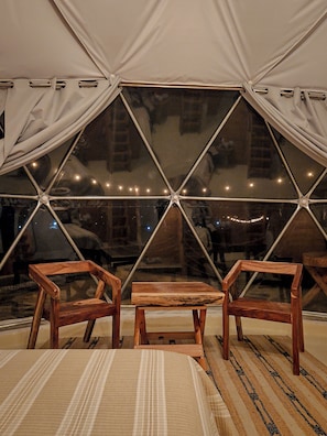Una tienda de campaña con un diseño de ventana geométrico, muebles de madera y una alfombra a rayas.