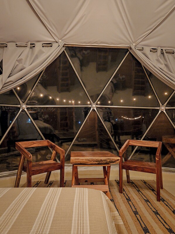 A tent with a geometric window design, wooden furniture, and a striped rug.