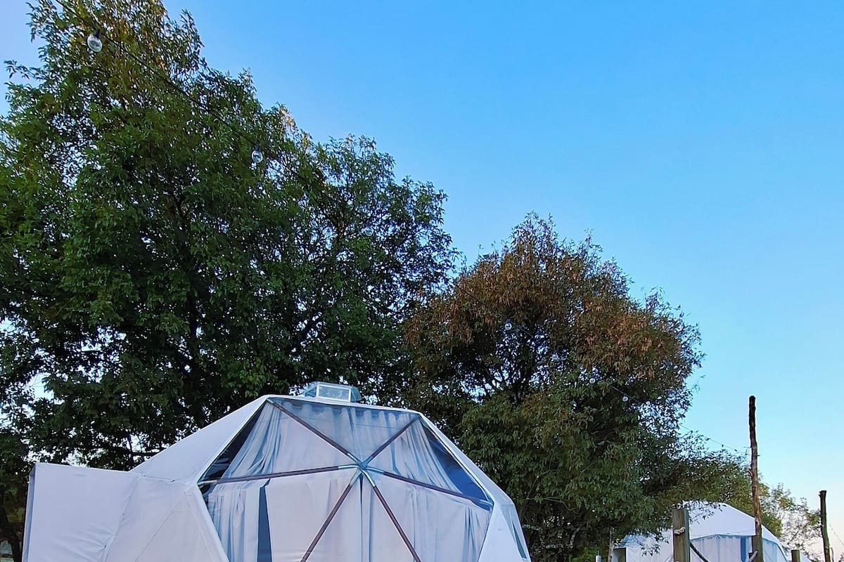 Una gran estructura en forma de cúpula geodésica con un recinto cubierto de malla delantera.