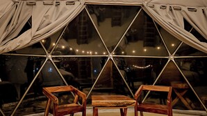 Una habitación con carpa, una mesa y dos sillas, ventanas amplias y luces colgantes.
