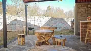 An outdoor patio area with stone walls, a wooden table, and benches.
