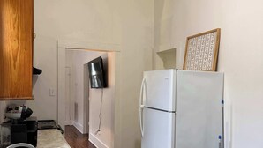 Eine Küche mit einem weißen Kühlschrank, Holzschränken, einem Spülbecken und einer hölzernen Bank.