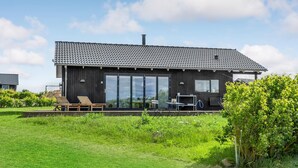 A modern house with a dark exterior, large sliding glass doors, and a small deck with seating. - Awesome home in Føllenslev with WiFi (Føllenslev)