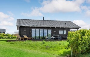 A modern house with a dark exterior, large sliding glass doors, and a small deck with seating. - Awesome home in Føllenslev with WiFi (Føllenslev)