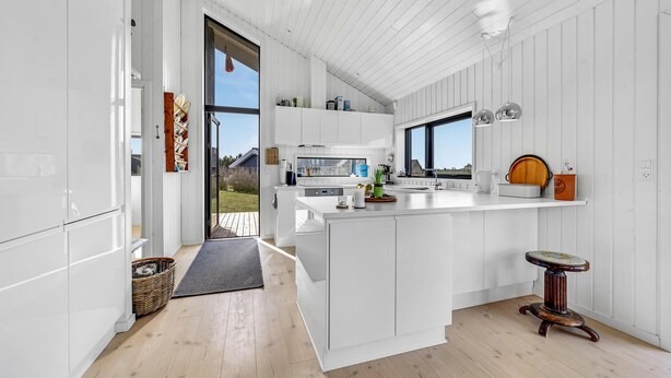 A modern kitchen with white cabinetry, a large island, and a view of the outdoors. - Awesome home in Føllenslev with WiFi (Føllenslev)