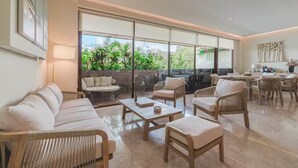 A spacious living area with a large sliding glass door leading to a balcony, furnished with a sofa, chairs, and a coffee table. - Near Tulum Beach 2BR –Private Pool & Cenote Access (Tulum)