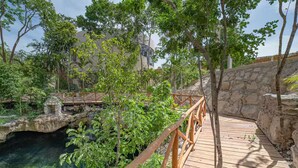 A wooden bridge over a clear water feature, surrounded by lush greenery and stone walls. - Near Tulum Beach 2BR –Private Pool & Cenote Access (Tulum)