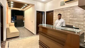A reception area with a glass counter, a sofa, and a ceiling fan. - Skyline Stay (Gurugram)