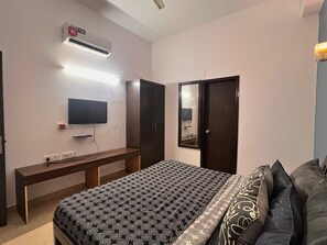 A bedroom with a bed, a TV, a wardrobe, and an air conditioning unit. - Skyline Stay (Gurugram)