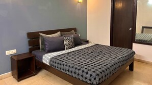 A bedroom with a bed, nightstands, a wardrobe, and wall-mounted lights. - Skyline Stay (Gurugram)