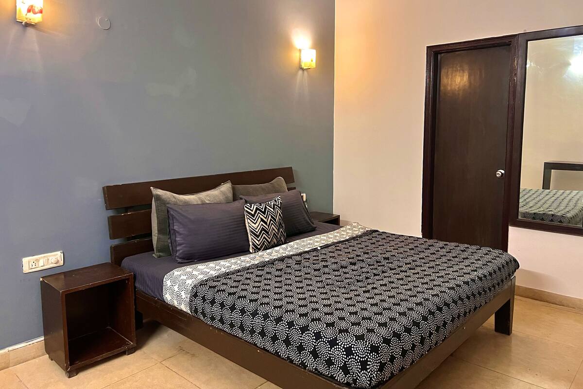 A bedroom with a bed, nightstands, a wardrobe, and wall-mounted lights.