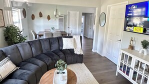 Een moderne woonkamer met een hoekbank, een ronde salontafel en een plafondventilator.