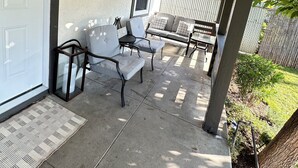 Een overdekt terras met een bankje, een klein tafeltje en een lantaarn.