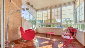 Une chambre moderne avec une chaise rouge, une petite table et un lampadaire.