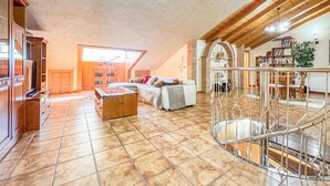Un vaste espace de vie doté d’un haut plafond, d’un télescope, d’un canapé et d’un escalier avec une rampe en verre.