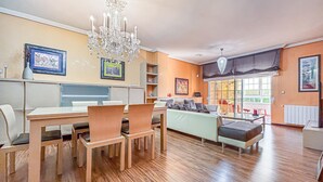 Un coin repas avec une table et des chaises en bois, un lustre et un canapé en arrière-plan.