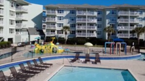 Ein Hotel mit Schwimmbad, Liegestühlen und einem Spielbereich für Kinder.