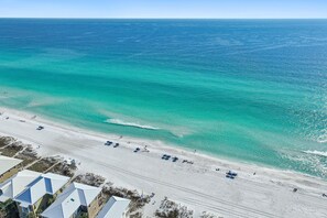 A beach with clear turquoise waters, a sandy shore, and buildings with white roofs. - Happy Go Lucky•Pool•Near Beach•Free Beach Chairs•Bikes•Beach Gear (Miramar Beach)