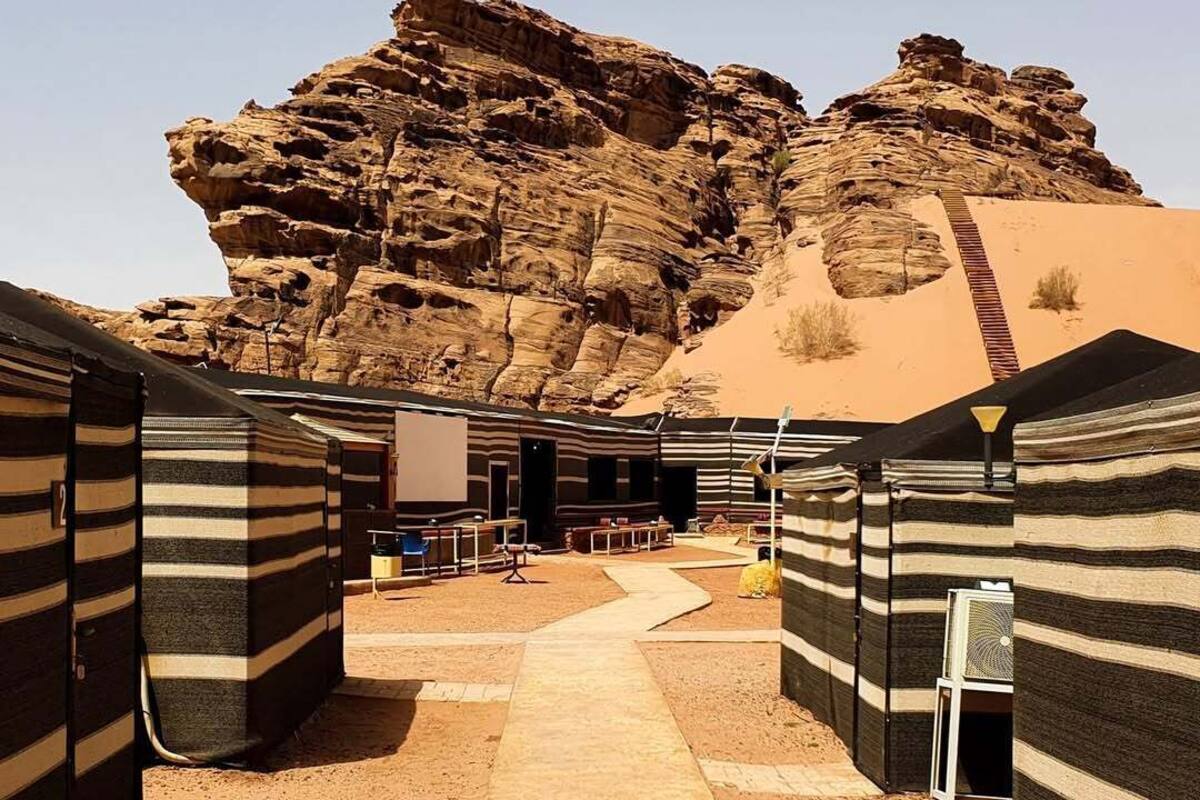 A desert hotel with striped rooms, a central walkway, and a large rock formation in the background.