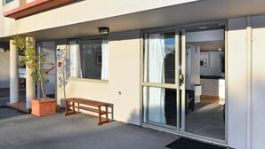 Un edificio con ingresso tramite vetrata scorrevole, una piccola zona relax all'aperto e una pianta in vaso.