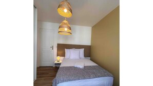 Et soveværelse med seng, sengebord, lampe og to hængende lamper.