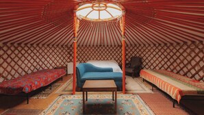 L’intérieur d’une yourte traditionnelle est aménagé avec un lit central, deux lits latéraux et une table en bois.