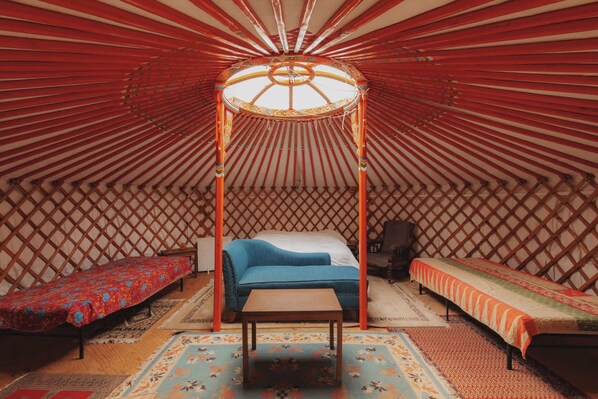 L’intérieur d’une yourte traditionnelle est aménagé avec un lit central, deux lits latéraux et une table en bois.