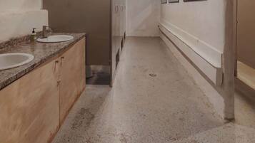 A narrow hallway with a sink and mirror on the left, wooden cabinets, and a sign indicating a water fountain.