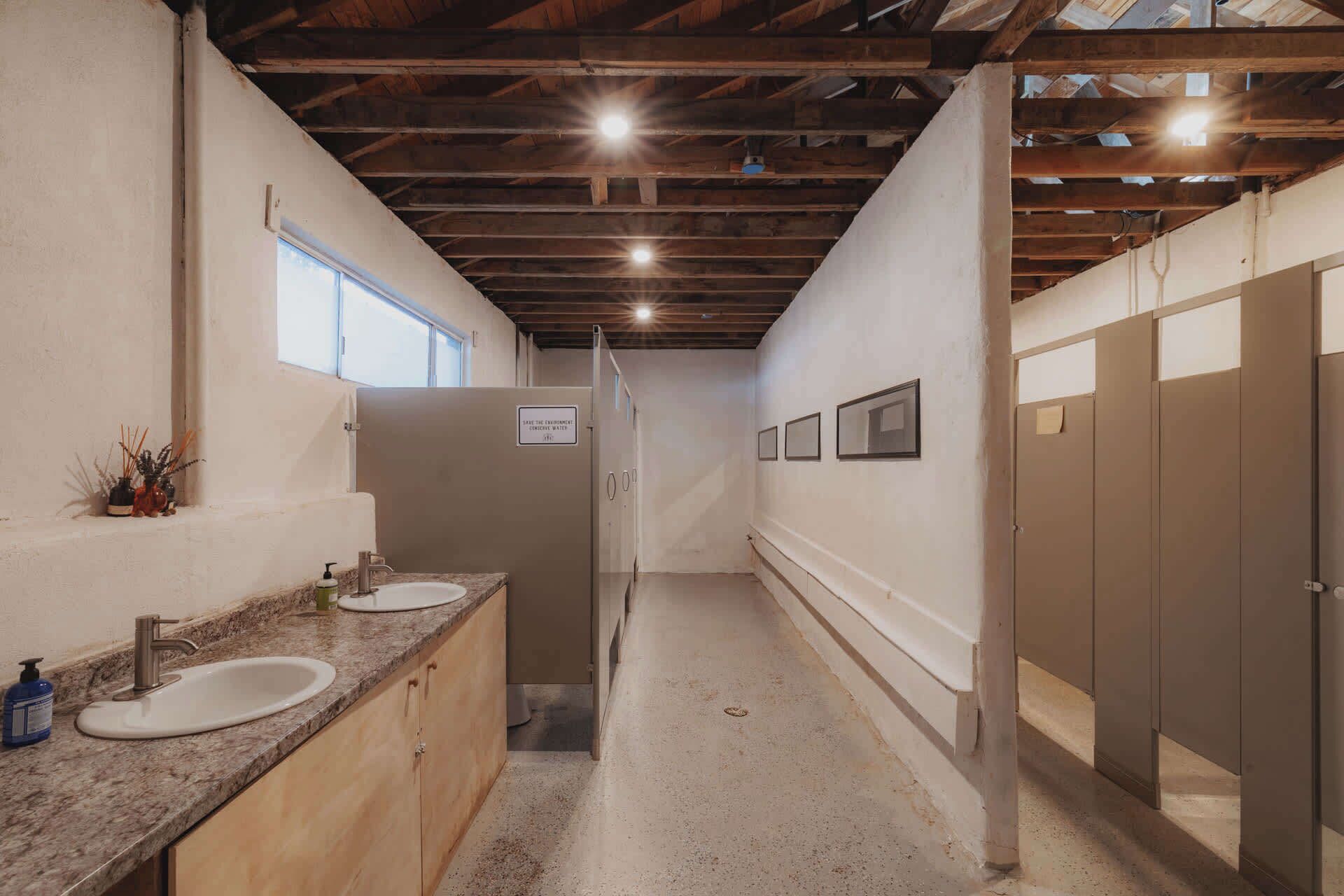 Ein schmaler Korridor mit zwei Waschbecken, Holzausbau und einer Decke mit freiliegenden Balken.