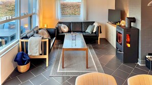 Una sala de estar moderna con un sofá de cuero negro, una mesa de centro de vidrio y una chimenea.