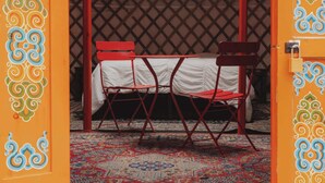 A traditional yurt with a bed and chairs, a patterned rug, and decorative wall designs. - Glamping yurt at nature retreat in Sequoia NForest (Dunlap)