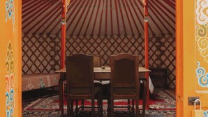 A traditional yurt interior with a central wooden table and chairs, a patterned rug, and a decorative ceiling. - Glamping yurt at a nature retreat Sequoia Highland (Dunlap)
