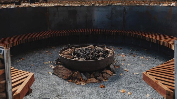 A circular fire pit with rocks and logs, surrounded by a brick border. - Glamping yurt at a nature retreat Sequoia Highland (Dunlap)