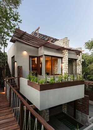 Ein modernes Haus mit einer Steinaußenwand, einer Holzterrasse und einem kleinen Garten.