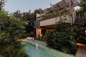 Ein modernes Mehrstöckige Gebäude mit Dachgarten, Schwimmbad und üppigem Grün rund um das Anwesen.
