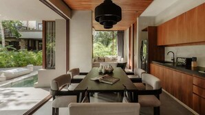 Un comedor moderno con una mesa larga, sillas y una lámpara colgante.