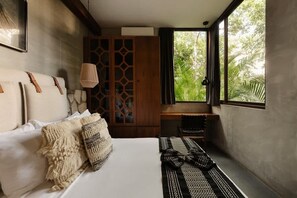 A bedroom with a bed, pillows, a woven rug, a wooden cabinet, and a window with a view of greenery. - Siwa Jungle Paradise Retreat C1-003 Beach Club (Tulum)